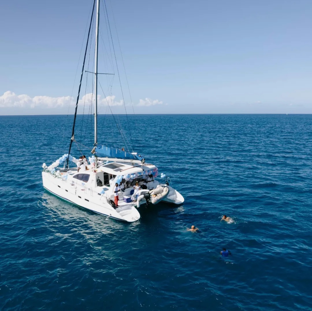 Yacht anchored with guests swimming in clear blue water